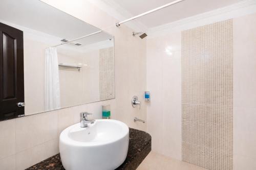 a white bathroom with a sink and a shower at Skylark Hotel by Gabrian Hotels in Gurgaon