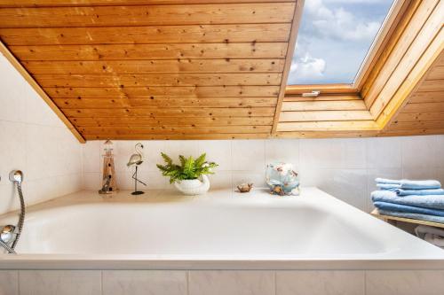 a large white tub in a bathroom with a skylight at Ferienwohnung Zum Leiselsee in Baunatal