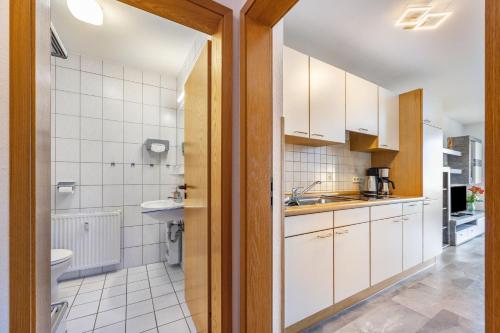 a kitchen with white cabinets and a sink and a toilet at Luv Lee Duhnen 06 in Cuxhaven