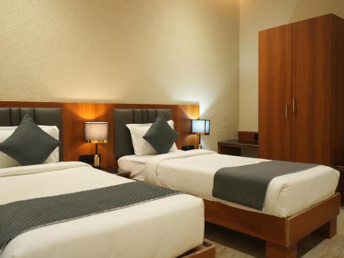 a hotel room with two beds and two lamps at Shreeja Central in Bhawānipatna
