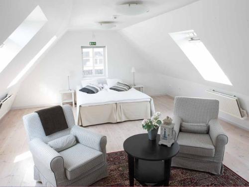 a bedroom with a bed and two chairs and a table at Blåsingsborgs Gårdshotell på Österlen in Kivik
