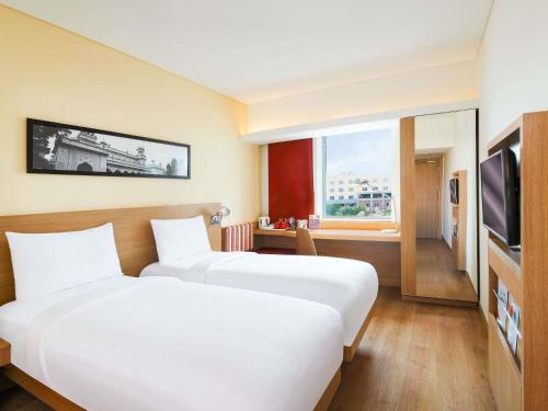 a hotel room with two beds and a television at ibis Navi Mumbai - An Accor Brand in Navi Mumbai