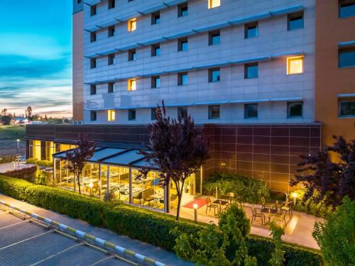 a hotel with tables and chairs outside of a building at Ibis Bursa in Bursa