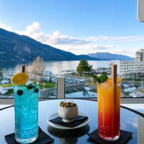 two cocktails sitting on a table with a view of the water at Logis Hôtel & Spa Marina d'Adelphia in Aix-les-Bains