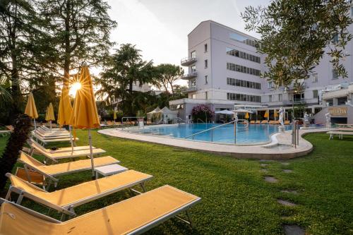 a hotel with a swimming pool with tables and umbrellas at Hotel Terme Helvetia in Abano Terme