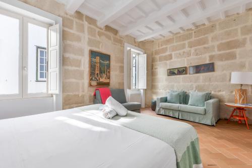 ein Schlafzimmer mit einem großen weißen Bett und Stühlen in der Unterkunft Suite 1 in Maó
