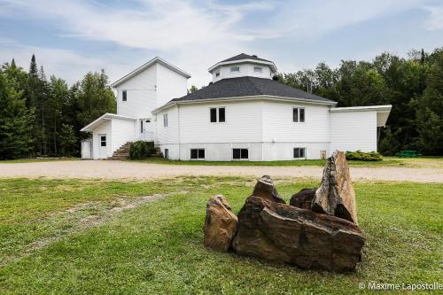 a large white house with a large rock in front of it at La Tour Boisée with Private Spa & Pool, Pool Table in Sainte Béatrix