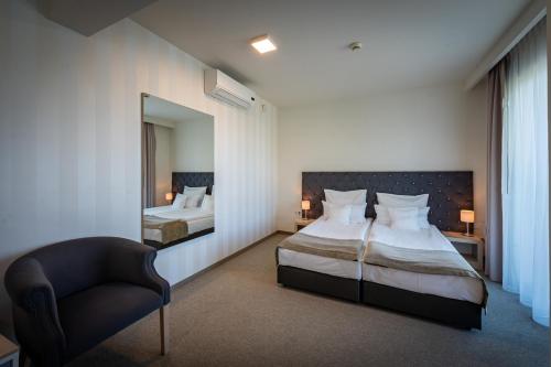 a bedroom with two beds and a chair and a mirror at Hotel Uniejów in Uniejow