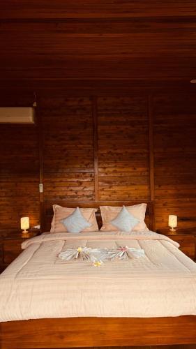 a large bed with white sheets and flowers on it at Mantra Guesthouse Sidemen in Sidemen