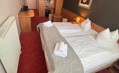 two beds in a hotel room with towels at DORMERO Express Hotel Passau in Passau