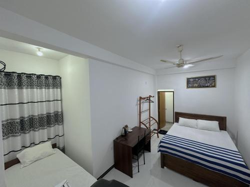 a bedroom with two beds and a dresser in it at White House Galaha in Galaha Town