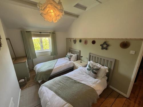 a bedroom with two beds and a chandelier at Copper Cottage in Devizes