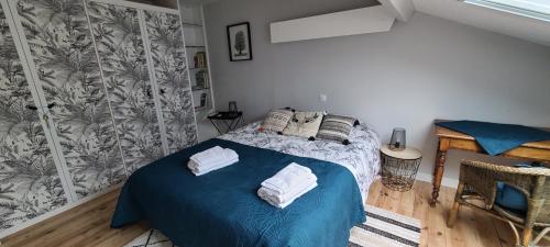 a bedroom with a blue bed with towels on it at L'annexe des Iris in Chaponost