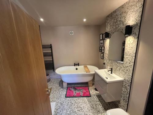 a bathroom with a tub and a sink and a toilet at Copper Cottage in Devizes