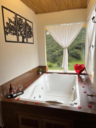 a large white tub in a bathroom with a window at Chalé Recanto da Grota in Passa Vinte