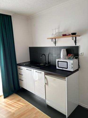 a kitchen with white cabinets and a microwave on a counter at Apartmani Daria in Ljubuški