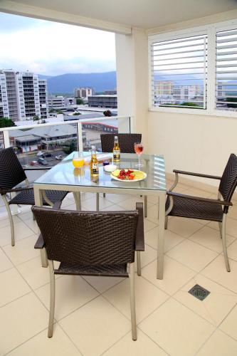 a table and chairs with a plate of food on it at Cairns Central Plaza Apartment Hotel Official in Cairns