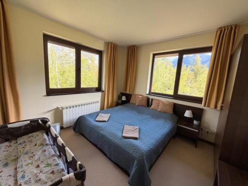 a bedroom with a blue bed and two windows at Apartments Terra Harmony - 4 star free SPA resort, Golf i Skiing in Bansko