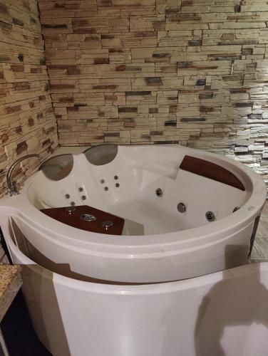 a white bath tub in a bathroom with a brick wall at Apartments Terra Harmony - 4 star free SPA resort, Golf i Skiing in Bansko