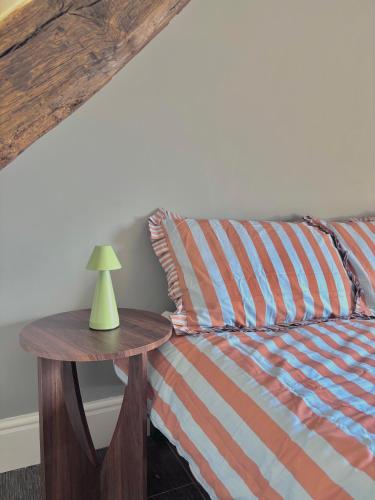 a bed with a table with a lamp on it at The Eaves - Pen Y Fan Views in Brecon