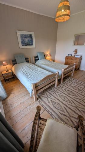 a bedroom with two beds and a rug at Manoir du Taillis in Heugon