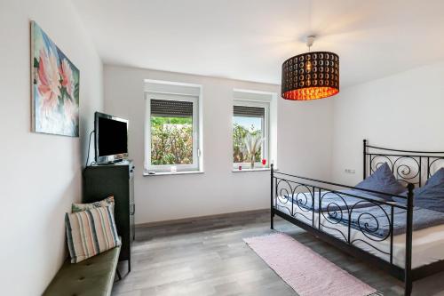 a bedroom with a bed and a tv and windows at Ferienwohnung Seeglück in Lauchhammer