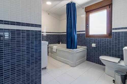 a blue tiled bathroom with a tub and a toilet at El Rincón de Denver 2 in Suances
