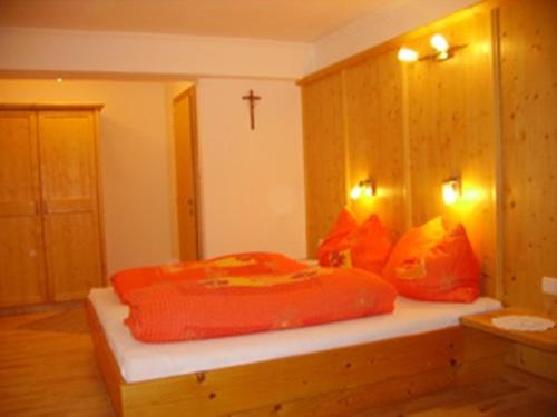 a bedroom with a bed with orange pillows and a cross at Komfortzimmer Widauer in Ebbs