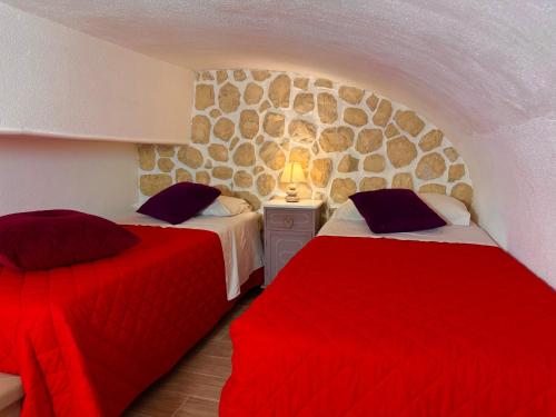 two beds in a room with a stone wall at Le Chalet Palermo Centro in Palermo