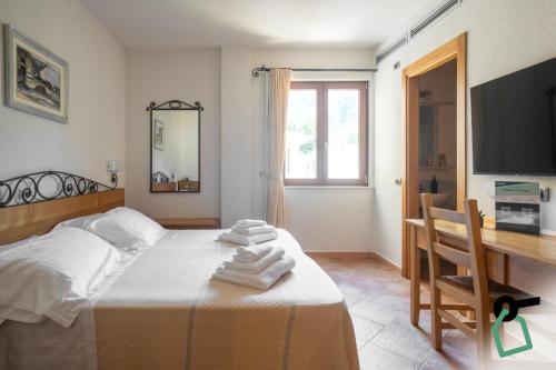 a bedroom with a bed and a desk and a television at Hotiday Cala Gonone in Cala Gonone