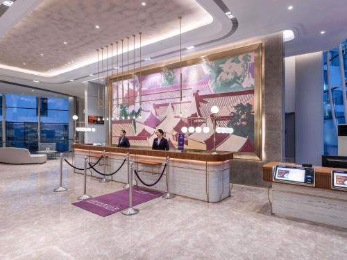 a lobby of a hotel with a large painting on the wall at Mercure Beijing Downtown in Beijing