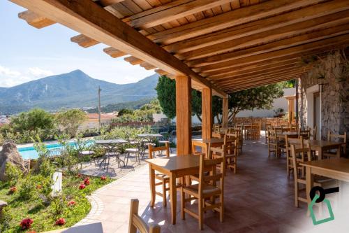a restaurant with tables and chairs and a pool at Hotiday Cala Gonone in Cala Gonone