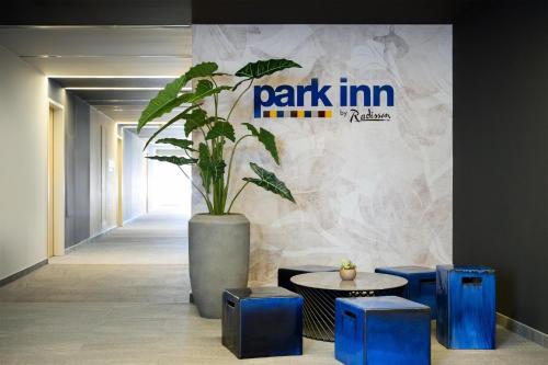a potted plant in a hallway with a table and stools at Park Inn by Radisson Sarvar Resort & Spa - All Inclusive in Sárvár