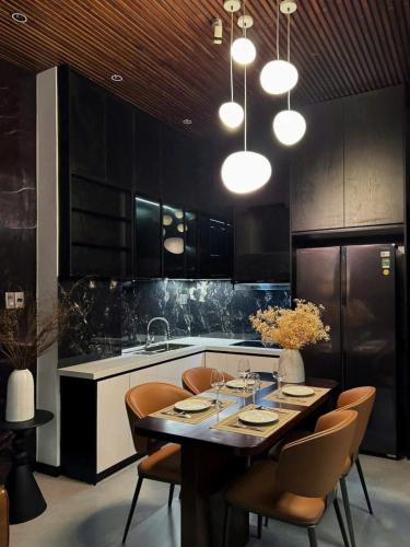 a kitchen with a table and chairs and a kitchen with black cabinets at MONO HAUS Villa Danang in Danang