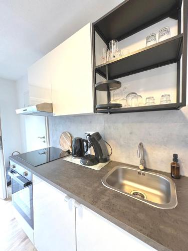 eine Küche mit Edelstahlspüle und weißen Schränken in der Unterkunft Hill-Suite in Cochem