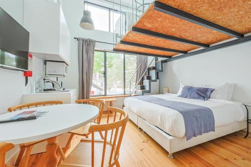 a bedroom with a bed and a table and a kitchen at Casa de São Bento by PURUS in Coimbra