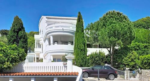 a white house with a car parked in front of it at Villa Perla Baska in Baška