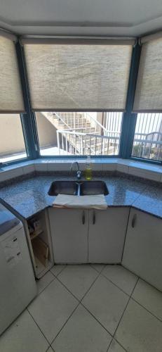 a bathroom with a sink in a room with windows at Millennium Mendoza pleno Centro 2 dormitorios, cocina completa, pileta y terraza in Mendoza