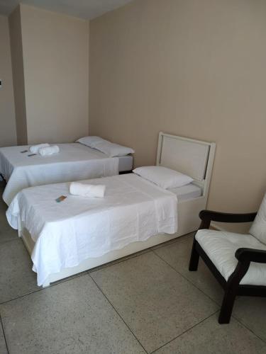two beds in a room with a chair and a couch at Loft Campinho 2 in Estação Inhoaíba