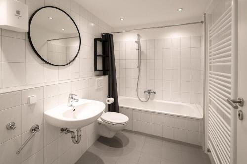 a bathroom with a sink and a toilet and a mirror at Pulheim Living 5 in Pulheim