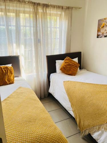 two beds sitting in a room with a window at Intsika apartments in Nelspruit