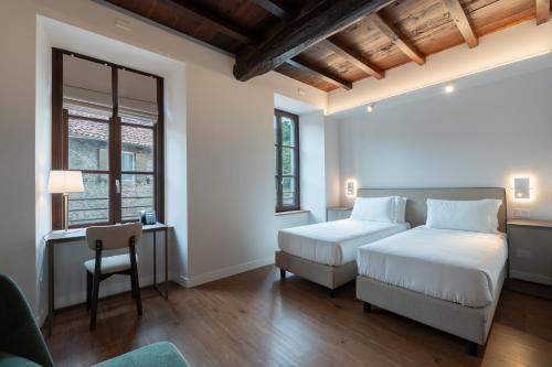 a hotel room with two beds and a chair at Hotel Cittadellarte in Biella