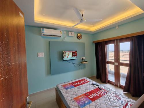 a room with a bed and a tv on the wall at Sathya Bay in Marakkānam