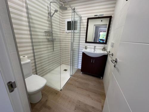 a bathroom with a toilet and a glass shower at Apartamento do Lagar, Praia da Abrela in O Vicedo