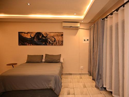 a bedroom with a bed and a painting on the wall at Gae Ga Monare Guest House in Burgersfort