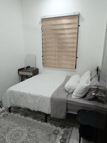 a bedroom with a bed with a window and a table at D'Berang Rumah Singgah in Kuala Berang