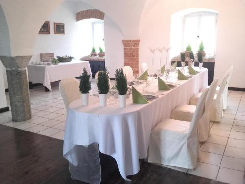a long table with white tables and chairs with plants on it at Zamek Rynkówka in Rynkówka