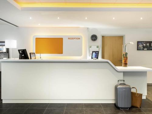 a lobby with a reception counter with a suitcase at ibis budget Aachen City in Aachen
