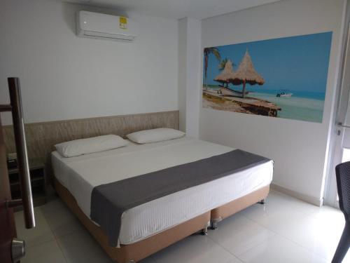 a bedroom with a bed with a painting on the wall at Hotel Baos in Sincelejo