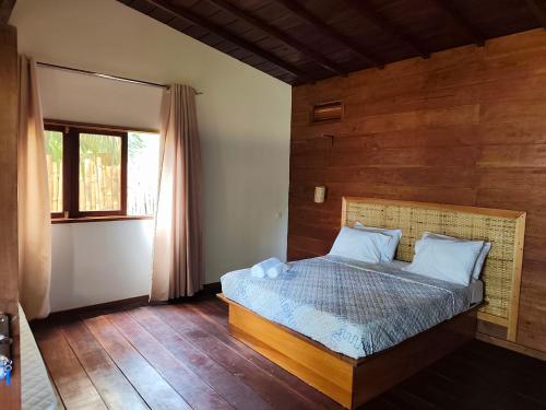 ein Schlafzimmer mit einem Bett und einer Holzwand in der Unterkunft Vila Anambo in Monteforte